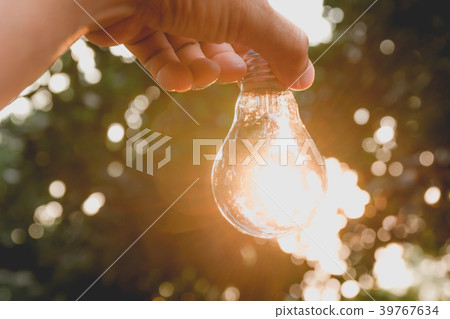 Hand holding light bulbs with glowing on ground. Hand holding light bulbs with glowing on ground. 39767634