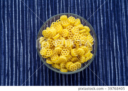 Macaroni ruote pasta in a glass bowl on a striped Macaroni ruote pasta in a glass bowl on a striped 39768405