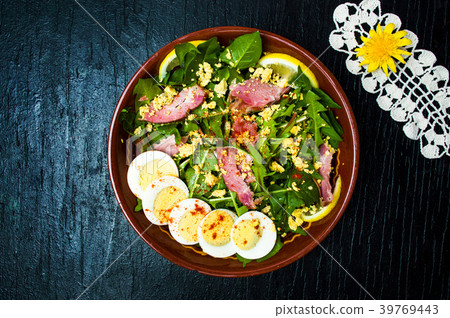 Dandelion salad with eggs meat and lemon in a bowl 39769443