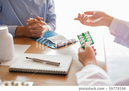 doctor hand holding tablet of drug and explain to patient in ho doctor hand holding tablet of drug and explain to patient in ho 39778586