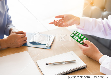 doctor hand holding tablet of drug and explain to patient in ho 39778587