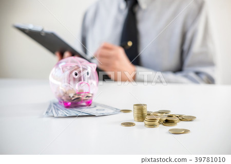 Businessman putting coins into piggy bank, writing to report and Businessman putting coins into piggy bank, writing to report and 39781010