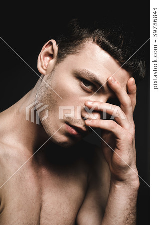 Demure man covering nose by hand Demure man covering nose by hand 39786843