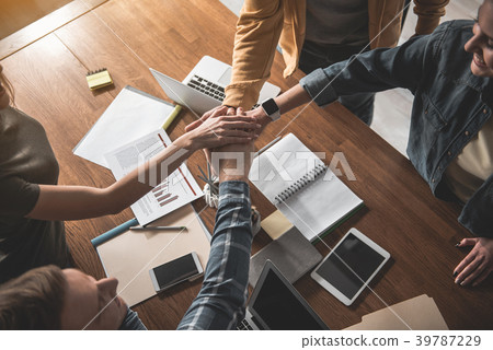 Young team putting arms together Young team putting arms together 39787229