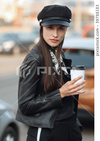 Girl walking along the street with cup of coffee Girl walking along the street with cup of coffee 39788183