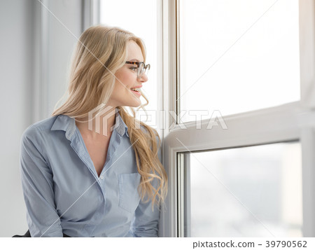 Cheerful businesswoman relaxing on windowsill 39790562