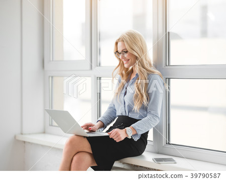 Joyful blond woman using computer for work near 39790587