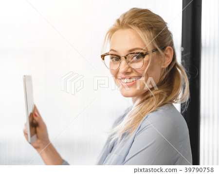 Happy young woman standing and holding tablet 39790758