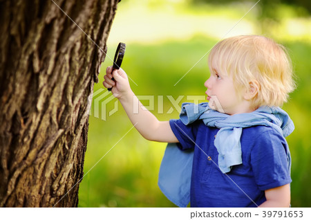 Charming kid exploring nature with magnifying glass Charming kid exploring nature with magnifying glass 39791653