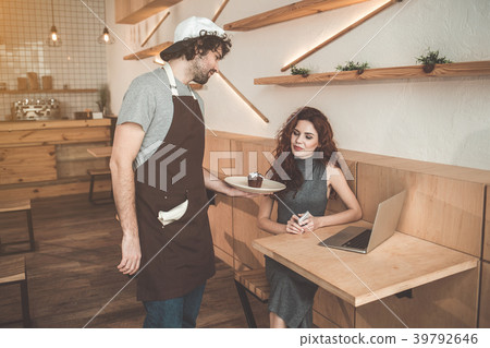 Pleasant waiter giving sweet dessert to client 39792646