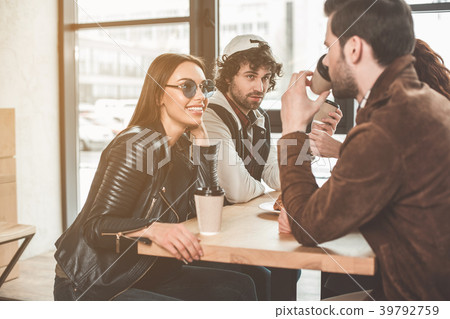 Joyful guys and girls speaking in coffee shop Joyful guys and girls speaking in coffee shop 39792759