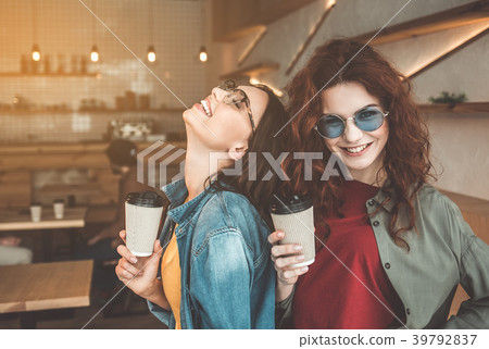 Cheerful two girls enjoying coffee in cafe 39792837