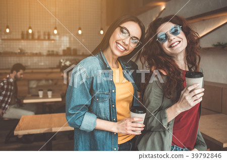 Pretty girls standing in cafeteria with cups of 39792846