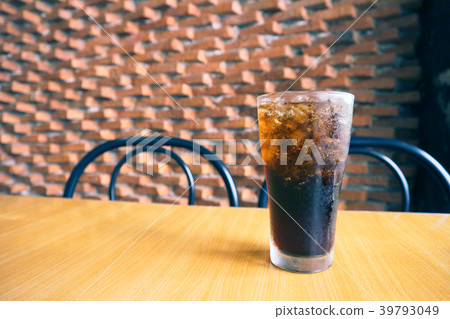 A glass of cola with ice on the table. 39793049
