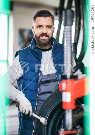 Man mechanic repairing a car in a garage. Man mechanic repairing a car in a garage. 39793265