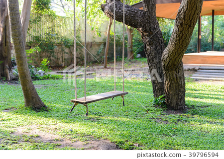 empty wooden swing hanging from a large tree 39796594