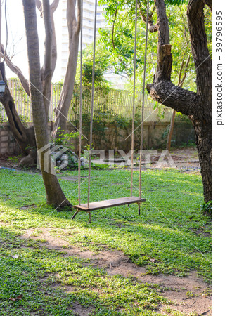 empty wooden swing hanging from a large tree empty wooden swing hanging from a large tree 39796595