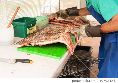 Cook prepares the meat to roast on the grill. Cook prepares the meat to roast on the grill. 39798421