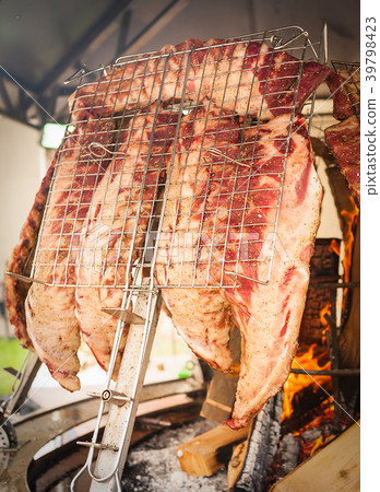 Roasted meat of beef cooked on a vertical grills. 39798423