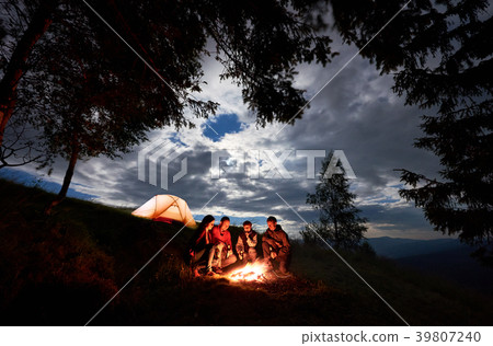 Four person are sitting around fire with beer near 39807240