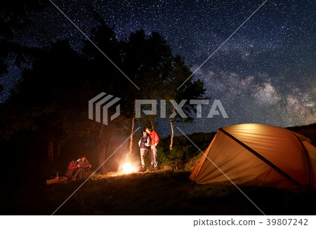 Two young couples at campfire under bright starry 39807242