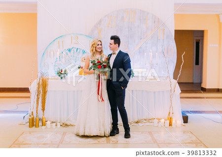 Happy young wedding couple posing with bouquet of 39813332