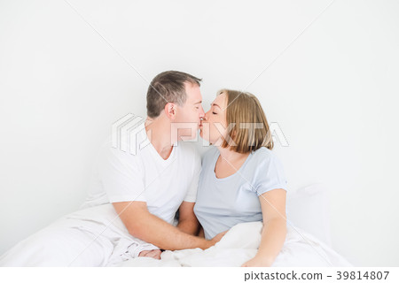 Kissing cute couple in sleepwear on the bed.  39814807