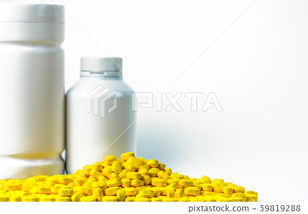 Pile of yellow tablets pills near pills bottle 39819288