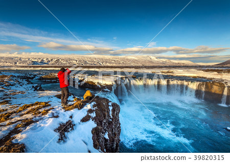 Photoghaper taking a photo at Godafoss waterfall. 39820315
