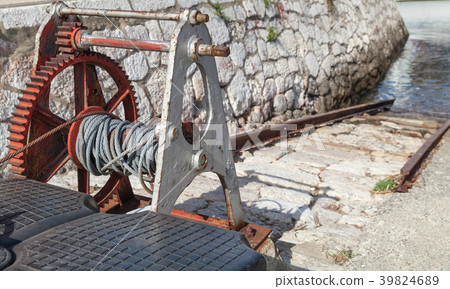 Old rusted winch, gangway in small port Old rusted winch, gangway in small port 39824689