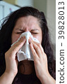 Woman blowing her nose hard into a tissue at home 39828013
