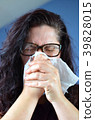 Woman blowing her nose hard into a tissue at home 39828015