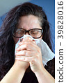 Woman blowing her nose hard into a tissue at home 39828016