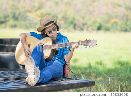 Woman wear hat and playing guitar on pickup truck Woman wear hat and playing guitar on pickup truck 39833698