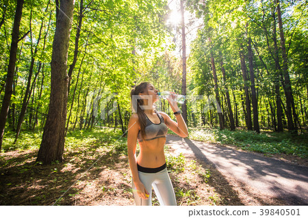 Young woman drinking water after running outdoors Young woman drinking water after running outdoors 39840501