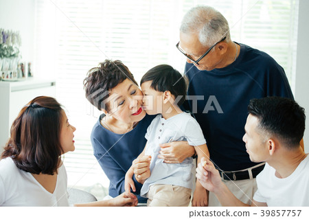 Boy kissing grandmother on cheeks with family 39857757