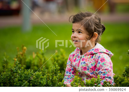 Little cute girl sitting in green bush in the park Little cute girl sitting in green bush in the park 39869924