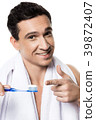 Handsome man with towel brushing his teeth.  39872407