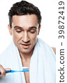 Handsome man with towel brushing his teeth.  39872419