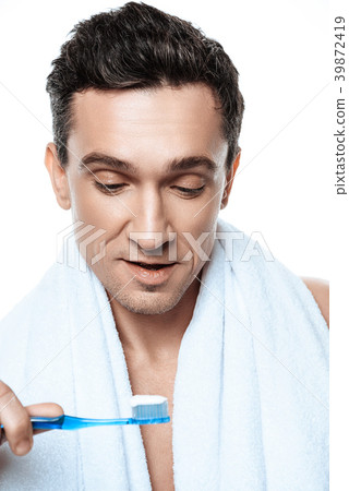 Handsome man with towel brushing his teeth. Handsome man with towel brushing his teeth. 39872419