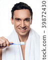 Handsome man with towel brushing his teeth.  39872430