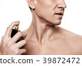 Handsome man using perfume isolated.  39872472