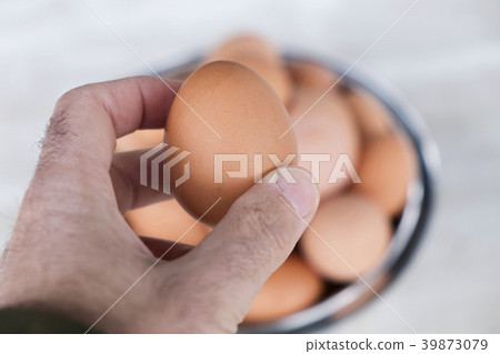 man with a brown egg in his hand 39873079