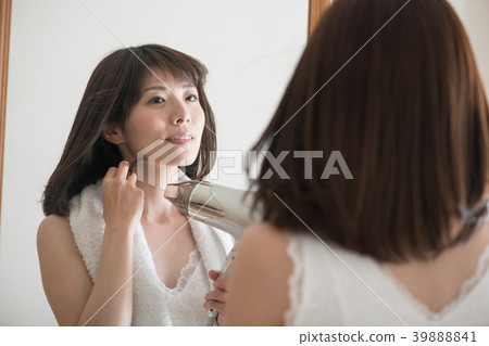 烘乾她的有烘乾機的年輕日本婦女頭髮 烘乾她的有烘乾機的年輕日本婦女頭髮 39888841