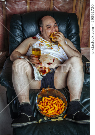 Overweight man eating and watching TV Overweight man eating and watching TV 39891720