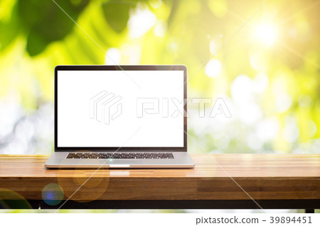 Laptop on wooden table in green garden lens flare 39894451