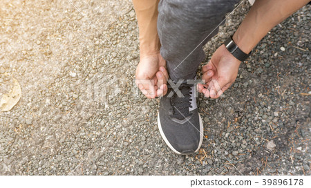 Men knelt down to do up his shoelaces 39896178