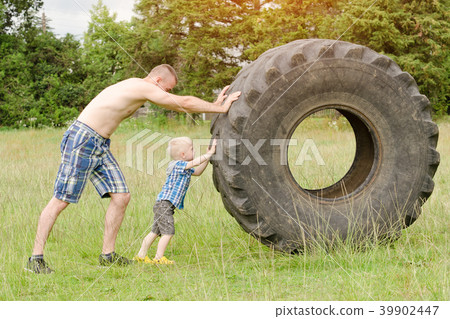 Dad and son push a big tire. Street workout Dad and son push a big tire. Street workout 39902447