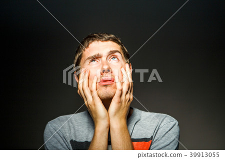 Photo of man in T-shirt with hands on chin 39913055