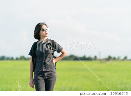 Woman with backpack hitchhiking along a road Woman with backpack hitchhiking along a road 39916945
